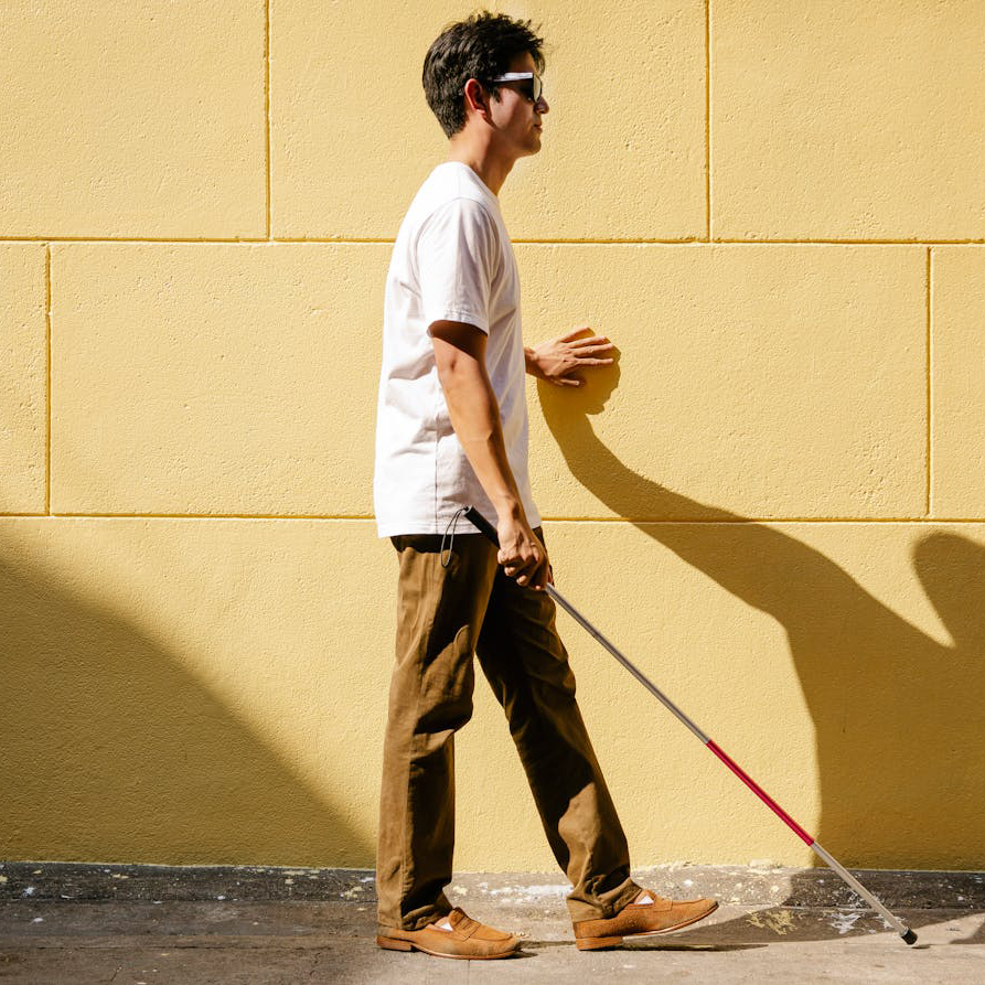 hombre joven ciego caminando con un baston